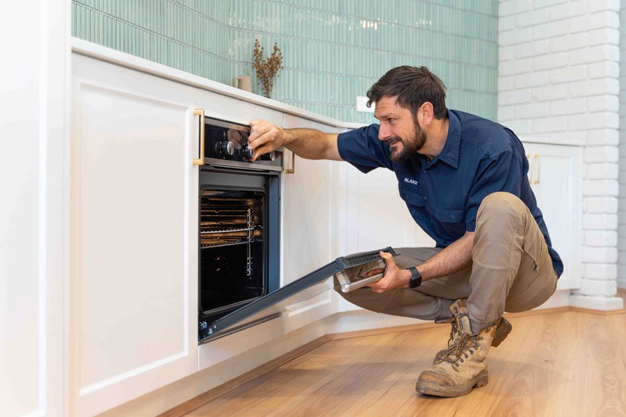 Electrician inspecting a kitchen oven installation in Gwelup home.