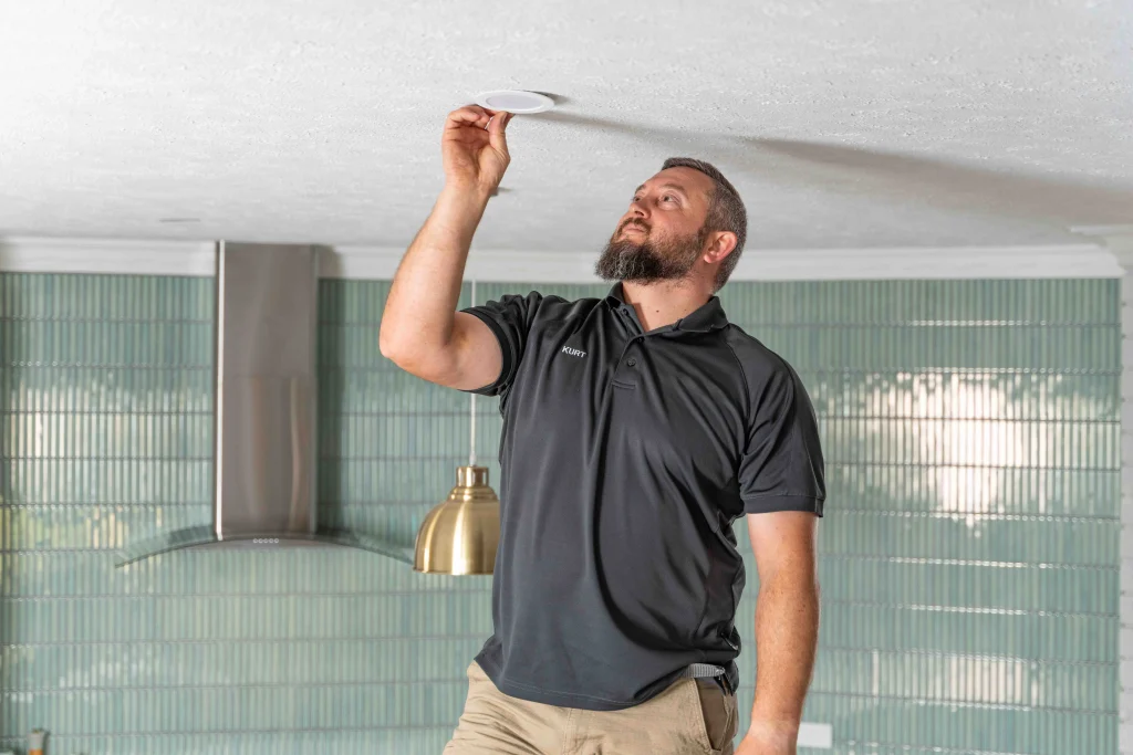 Electrician installing a ceiling light in a modern Gwelup kitchen.
