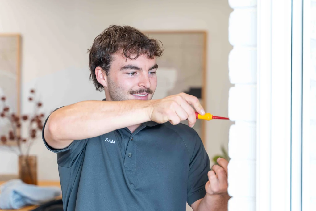 Professional electrician in uniform testing a circuit breaker panel