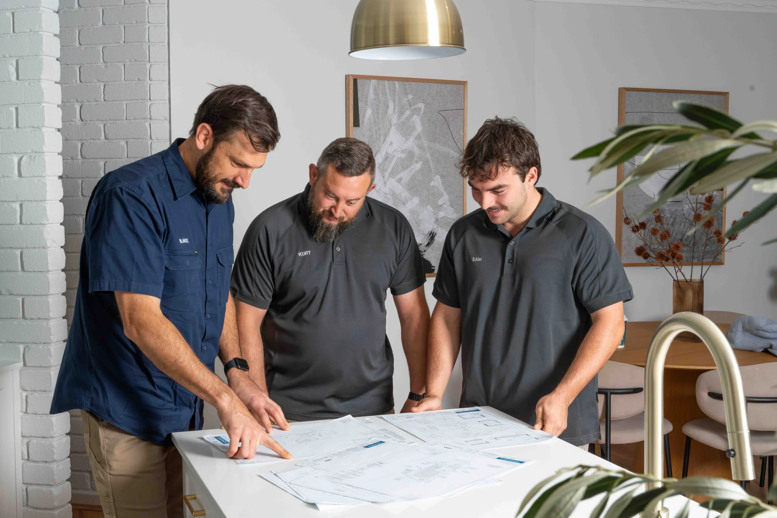Electricians reviewing plans at a Gwelup electrical business workstation.